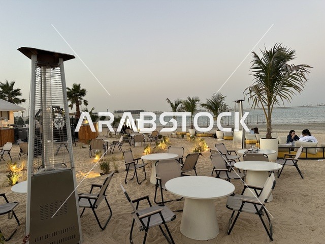 أشجار نخيل أضواء صغيرة حول جذوعها، سولت البحر وجهة ترفيهية وشاطئية عائلية تقع على طريق الكورنيش في الخبر في المملكة العربية السعودية، تجديدات إضافية وتطويرات في 3  يناير 2026، شاطئ رملي مع وجود مظلات وأشجار نخيل