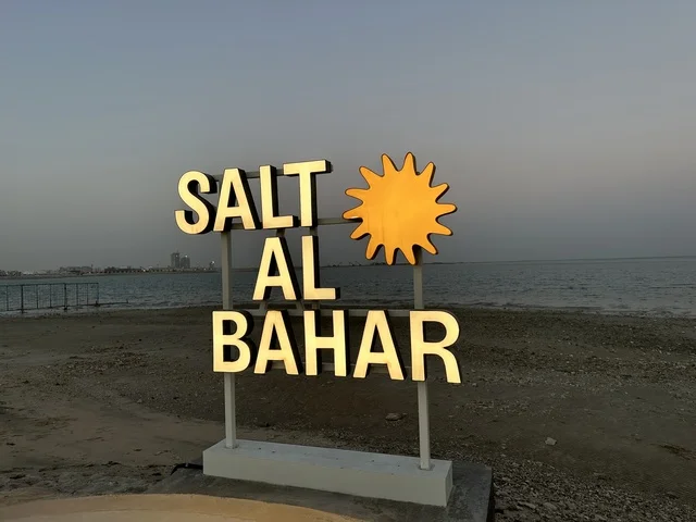 لافتة لمشروع سياحي أو منتجع يحمل اسم المكان، سولت البحر وجهة ترفيهية وشاطئية عائلية تقع على طريق الكورنيش في الخبر في المملكة العربية السعودية، تجديدات إضافية وتطويرات في 3  يناير 2026، شاطئ رملي مع وجود مظلات وأشجار نخيل