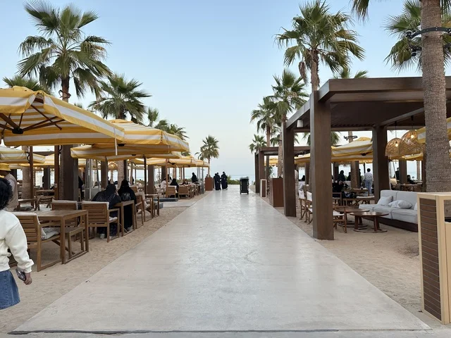 People are sitting and relaxing in the area, Solt Al-Bahr is a recreational and family beach destination located on the Corniche Road in Khobar, Saudi Arabia, a sandy beach with umbrellas and palm trees, additional renovations and developments on January 3, 2026.