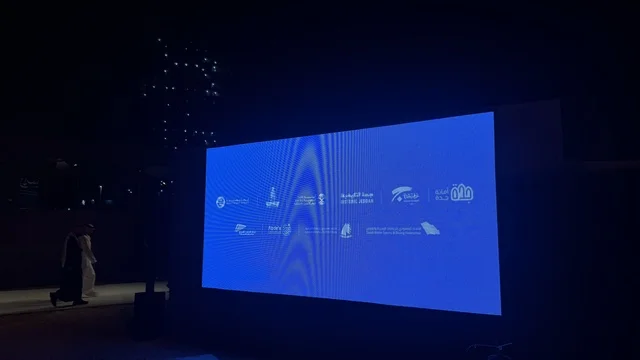 شاشة عرض كبير في مهرجان السفن الخشبية على شاطئ الحمراء بجدة في المملكة العربية السعودية 12 إلى 16 يناير 2026، عروض لمراحل بناء السفن التقليدية والأدوات والمواد المستخدمة،  التراث البحري والهوية الساحلية، الأنشطة التفاعلية والعروض الثقافية