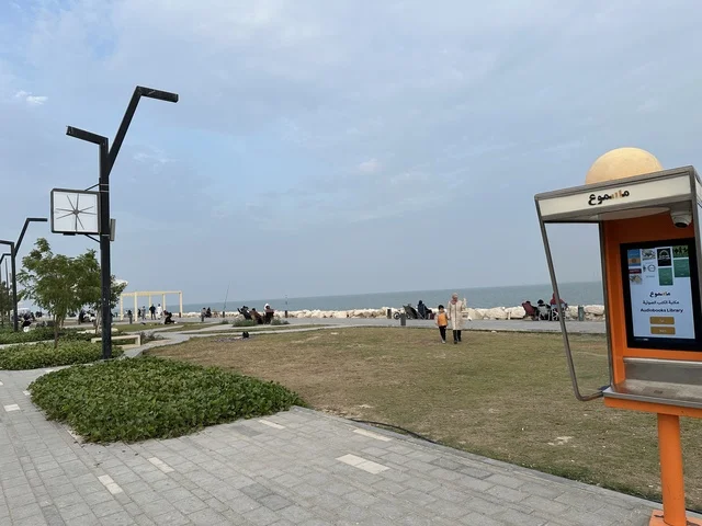 The audio library cabins "Masmoo" in the Hams Walkway in the Eastern Province, Saudi Arabia, offer a calm family atmosphere, walking and relaxation spaces, an open entertainment destination, a modern strolling experience, and outdoor seating and benches.