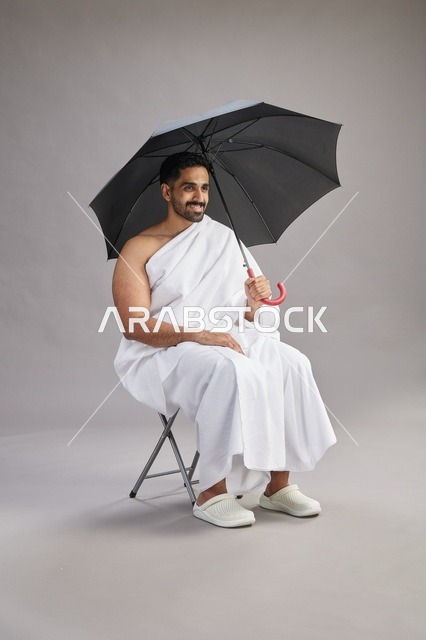 رجل سعودي بملابس الإحرام مع مظلة في الاستوديو