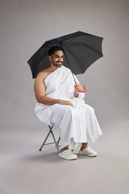 رجل سعودي بملابس الإحرام مع مظلة في الاستوديو