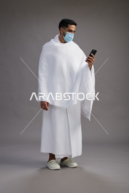 Arab Man in Ihram Using Smartphone with Face Mask