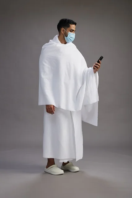 Arab Pilgrim in Ihram with Smartphone and Face Mask