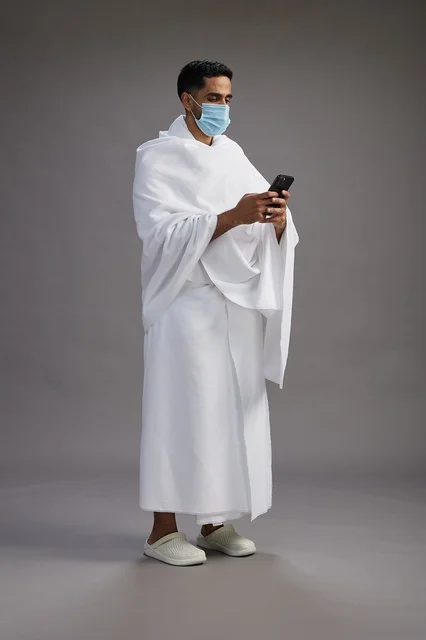 Saudi Man in Ihram Using Smartphone with Face Mask