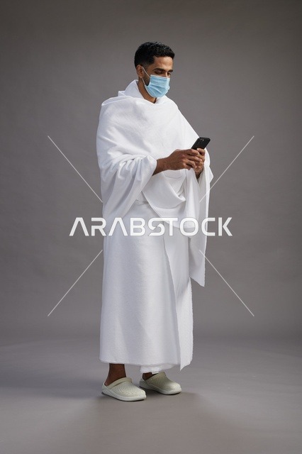 Arab Man in Ihram Using Smartphone with Face Mask