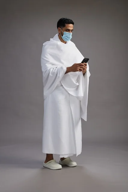 Arab Man in Ihram Using Smartphone with Face Mask