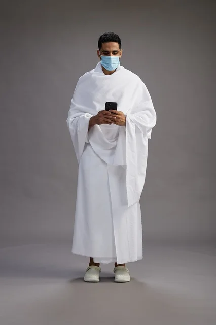 Arab Man in Ihram Using Smartphone with Face Mask
