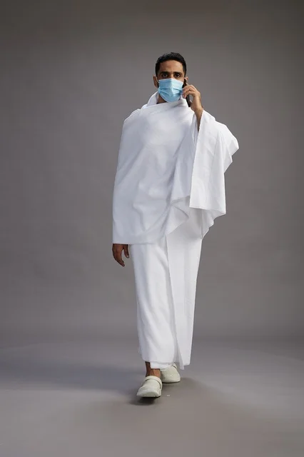 Saudi Man in Ihram with Face Mask Using Smartphone