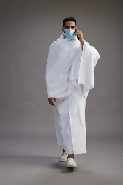 Saudi Man in Ihram Wearing Face Mask with Smartphone