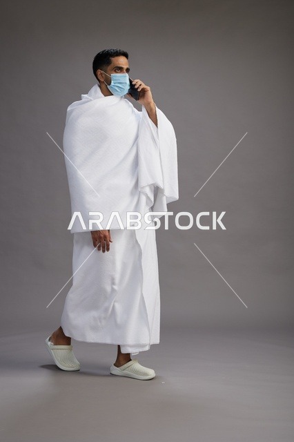 Arab Man in Ihram Using Smartphone with Face Mask