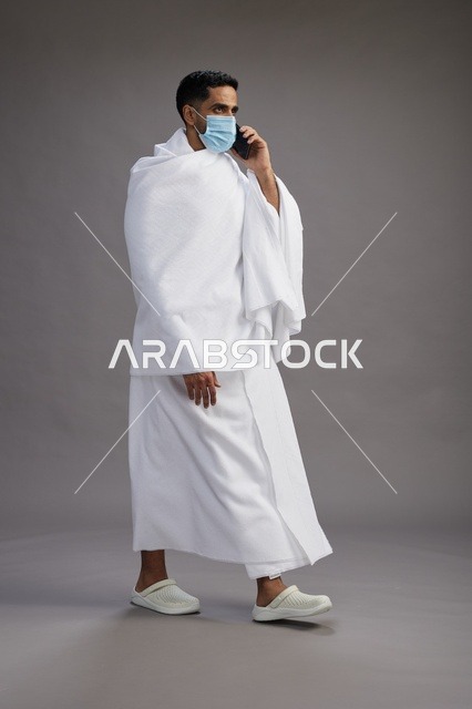 رجل سعودي بملابس الإحرام يستخدم الهاتف المحمول