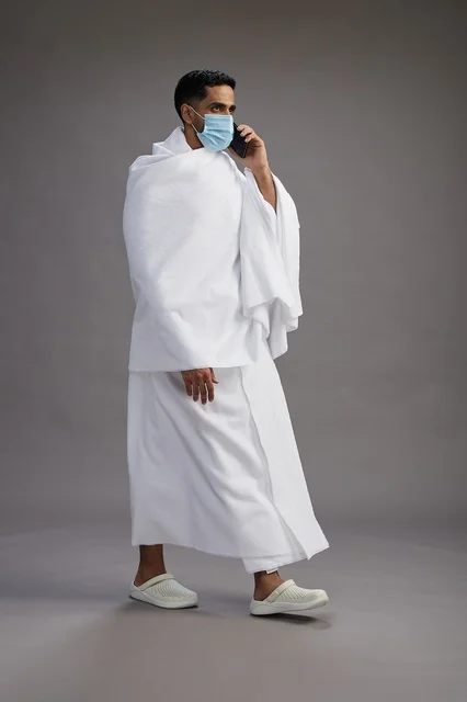 Saudi Pilgrim in Ihram Using Smartphone
