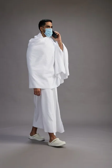 Saudi Man in Ihram with Face Mask on Smartphone