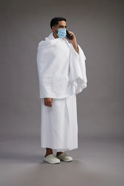Arab Pilgrim in Ihram with Smartphone and Mask
