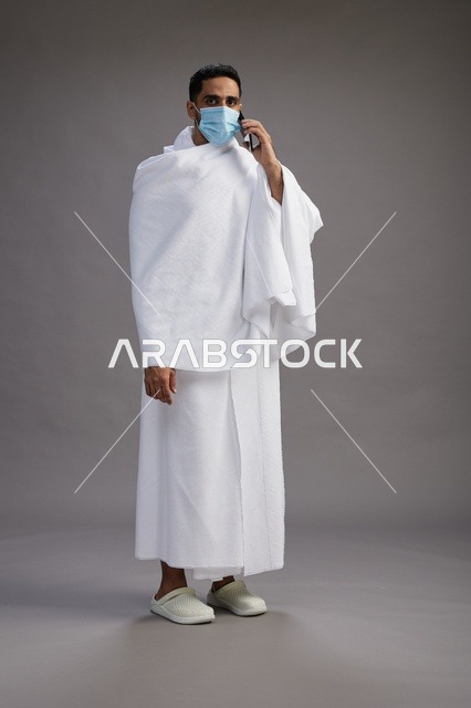 Saudi Man in Ihram Using Phone with Face Mask