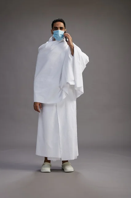 Saudi Man in Ihram Using Phone with Face Mask