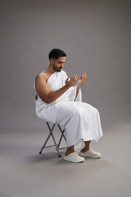 حاج سعودي بملابس الإحرام يرفع يديه للدعاء في الاستوديو