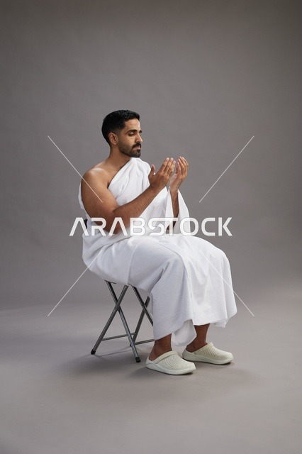 حاج سعودي بملابس الإحرام يرفع يديه للدعاء