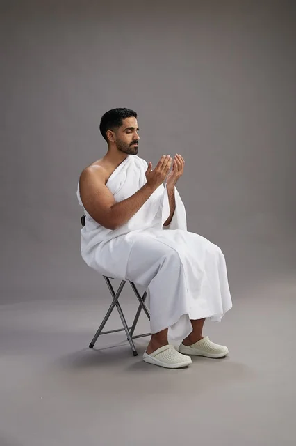 حاج سعودي بملابس الإحرام يرفع يديه للدعاء