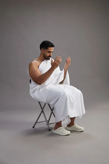 حاج سعودي يرتدي ملابس الإحرام ويجلس للدعاء في الاستوديو