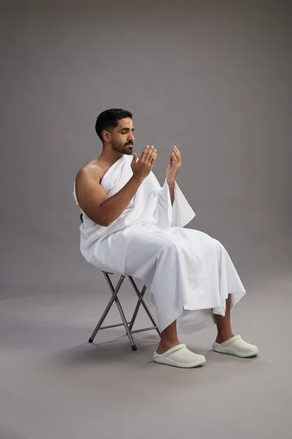 حاج سعودي بملابس الإحرام يدعو في الاستوديو