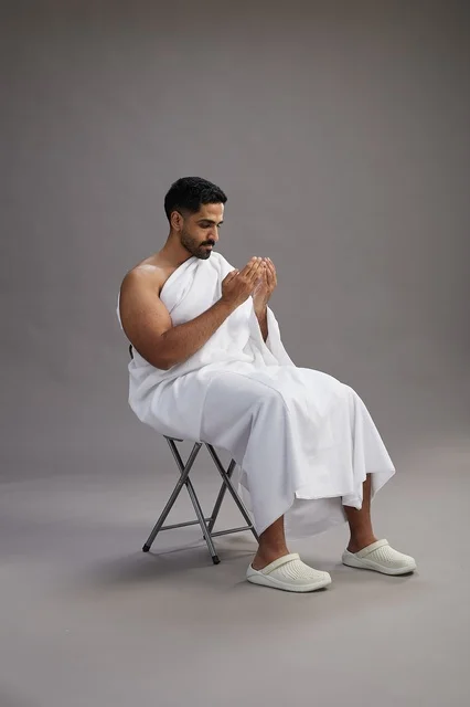 حاج سعودي بملابس الإحرام يدعو على خلفية رمادية