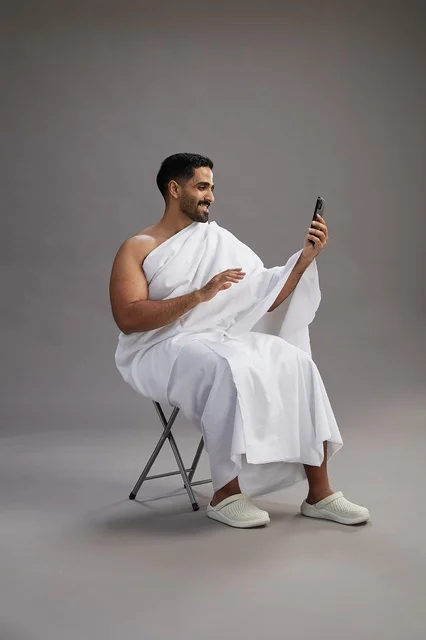 حاج سعودي بملابس الإحرام يجري مكالمة فيديو بالهاتف