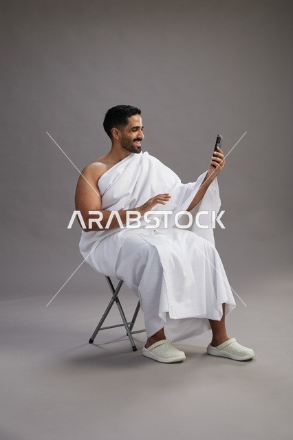 حاج سعودي بملابس الإحرام يجري مكالمة فيديو بالاستوديو