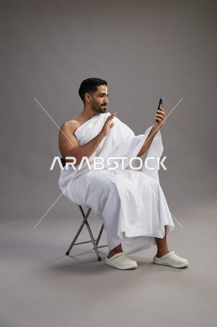 حاج سعودي بملابس الإحرام يجري مكالمة فيديو بالهاتف