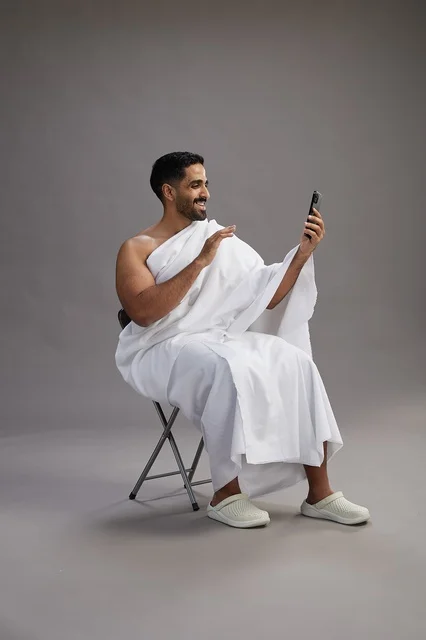 حاج سعودي بملابس الإحرام يجري مكالمة فيديو بالهاتف