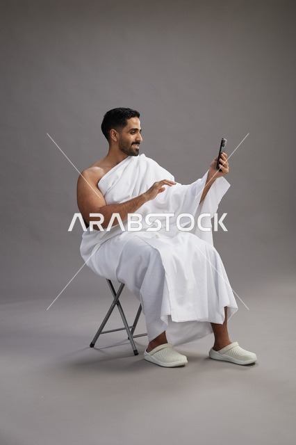 حاج سعودي بملابس الإحرام يجري مكالمة فيديو بالهاتف
