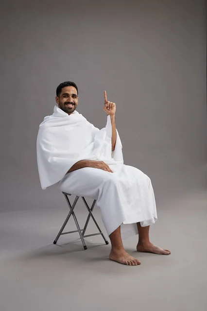 حاج سعودي بملابس الإحرام جالس حافي القدمين ومبتسم