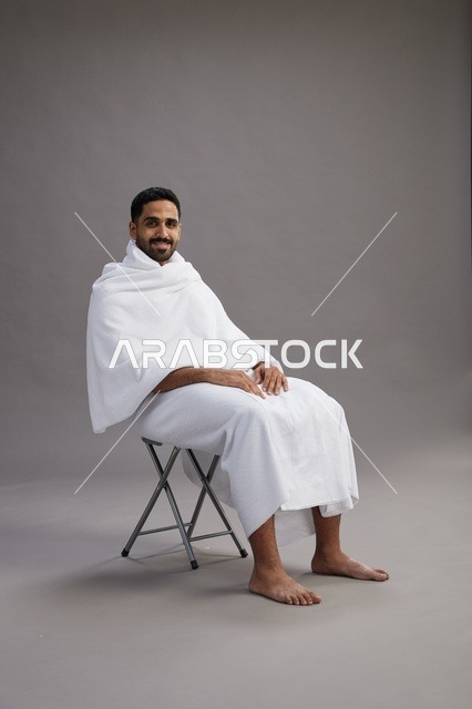 حاج سعودي بملابس الإحرام جالس على كرسي بالاستوديو