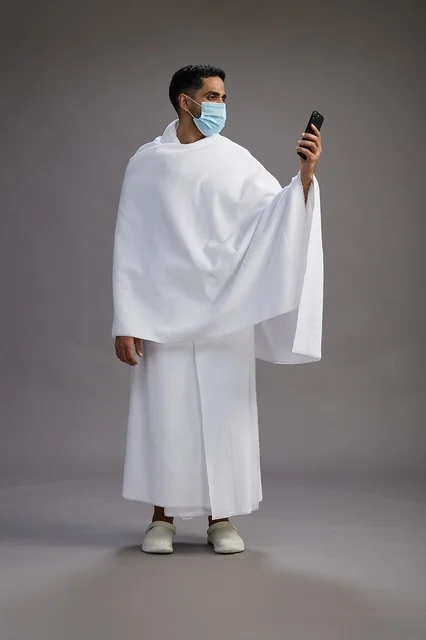 Saudi Pilgrim in Ihram Wearing Mask Using Smartphone