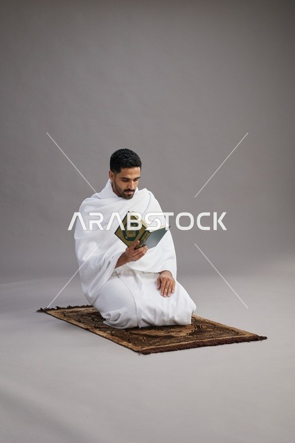 Saudi Pilgrim in Ihram Reading Quran on Prayer Rug