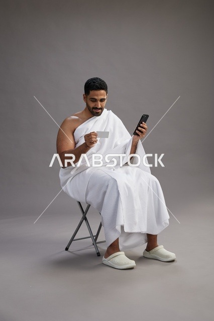 حاج سعودي بملابس الإحرام يجري عملية دفع إلكتروني