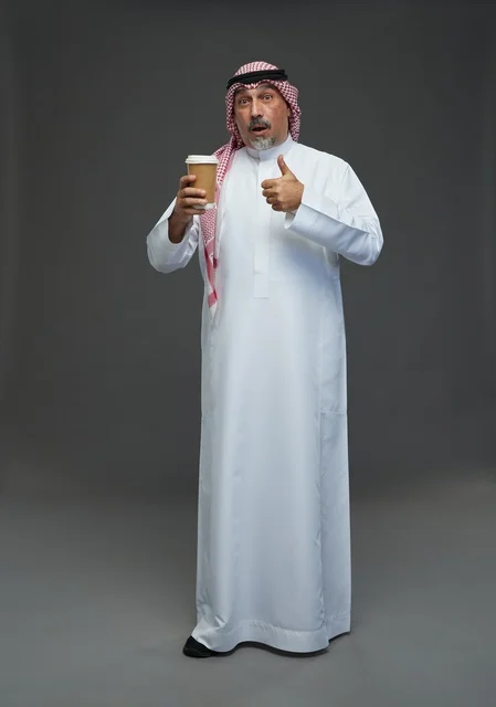 رجل  عربي سعودي خليجي مسن يرتدي الزي الثوب الابيض والشماغ ويحمل فنجان قهوة,  ايماءات واشارات مختلفه , كامل الجسم, خلفيه رماديه