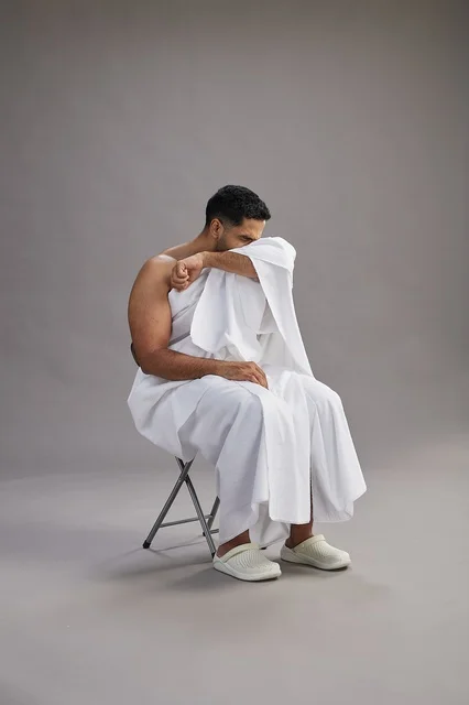 Saudi Man in Ihram Sneezing and Covering Mouth in Studio