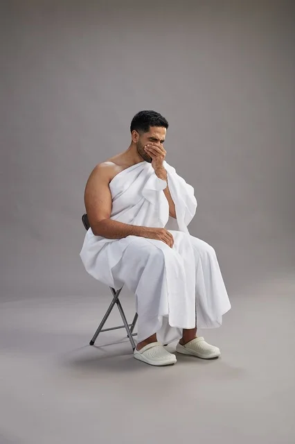 رجل سعودي بملابس الإحرام يعطس في الاستوديو