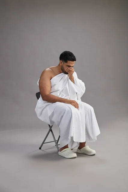 رجل سعودي بملابس الإحرام يعطس على خلفية رمادية