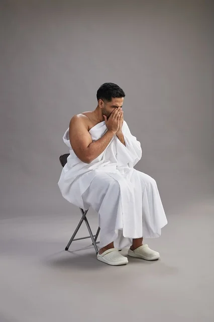 Saudi Man in Ihram Sneezing on Grey Background