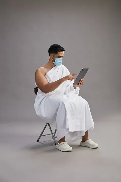 Saudi Man in Ihram Using Tablet with Face Mask