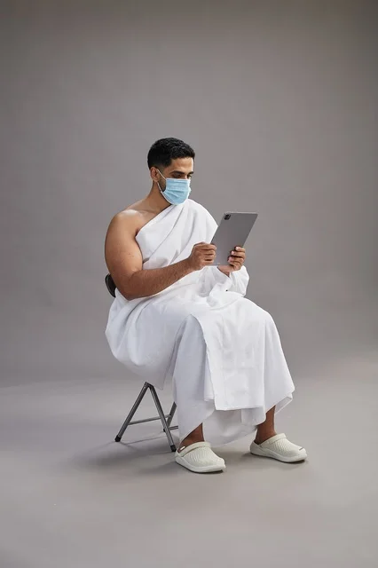 Saudi Man in Ihram Using Tablet with Face Mask