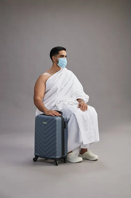Saudi Pilgrim in Ihram with Suitcase and Mask