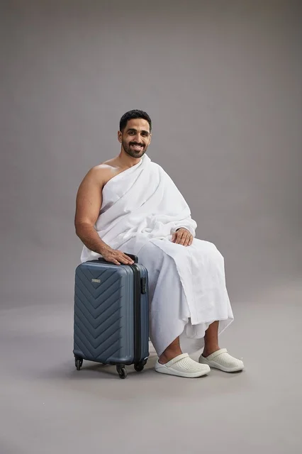 Saudi Man in Ihram Sitting with Suitcase Studio Portrait