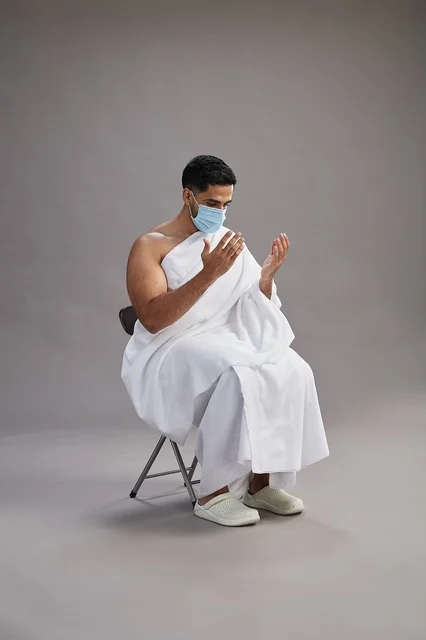 رجل سعودي بملابس الإحرام والكمامة يدعو