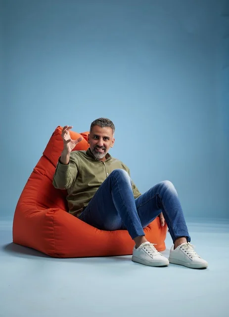 Man Sitting in Orange Bean Bag on Blue Background