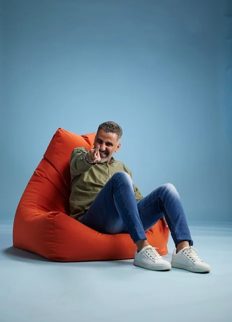 رجل في منتصف العمر يشير بإصبعه من مقعد استرخاء برتقالي